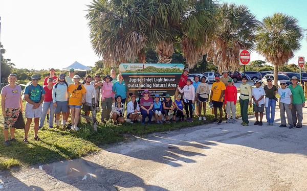 large group of volunteers pose around the Jupiter Lighthouse Outstanding Natural Area sign