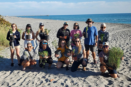 volunteer group dressed for working on the beach pose at the beach in Jupiter, Florida